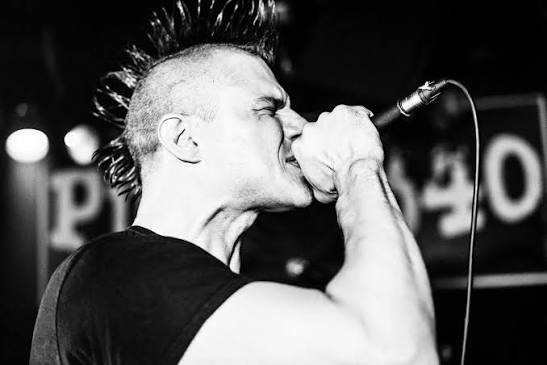 Bound By None's vocalist singing into the microphone at a Vancouver punk show